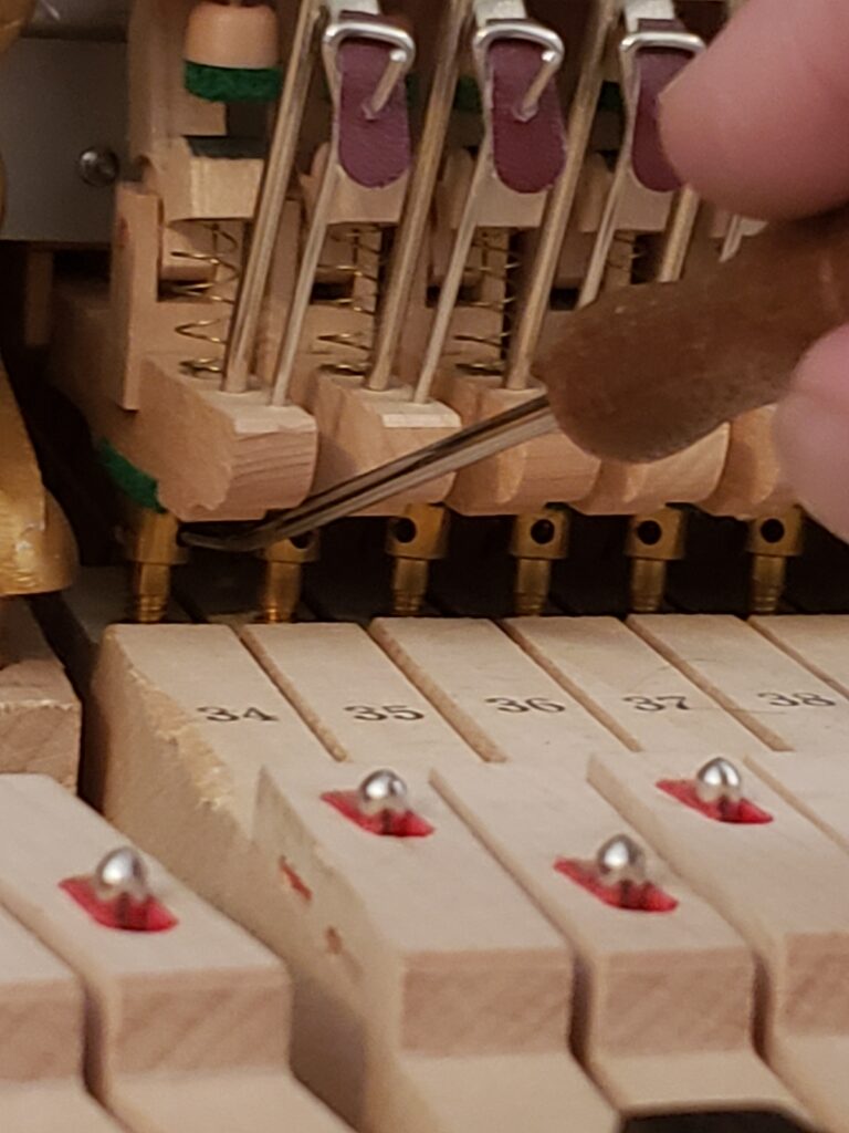 Master Piano Technician Joe Kemple adjusting capstans on a grand piano.